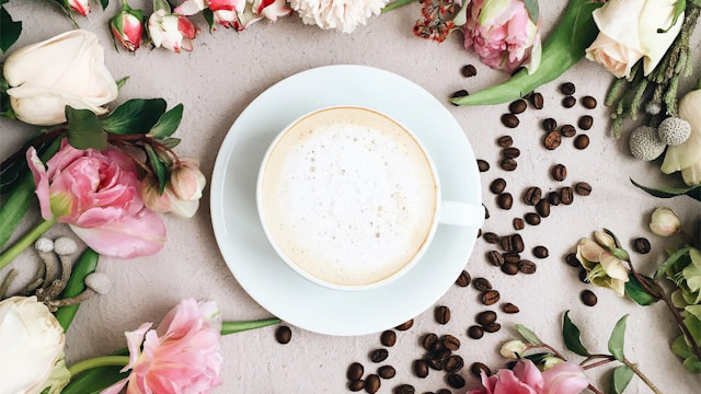 A cup of coffee surrounded by flowers
